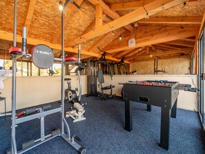 Ein Fitnessraum mit Trainingsgeräten, einem Tischfußballspiel und einem Fenster mit Blick.