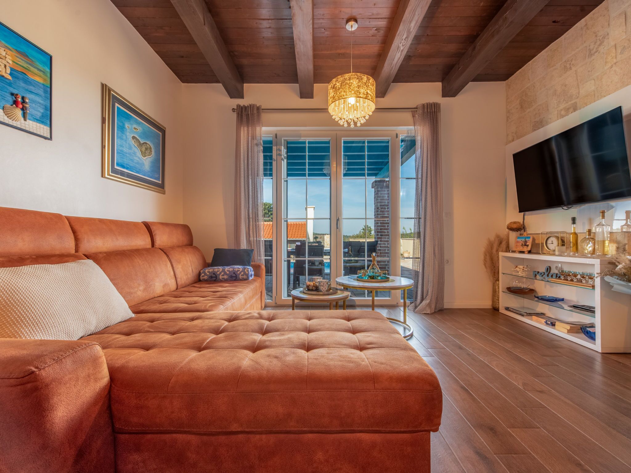 A spacious living room with a large leather sofa, a television mounted on the wall, and a dining area with a table and chairs.