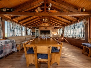 A spacious dining area with a long wooden table and benches, flanked by windows with patterned curtains. - Villa Jurenda with heated pool by Interhome (Debeljak)