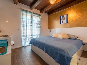 Ein Schlafzimmer mit Bett, Schreibtisch und einem Vorhangfenster.