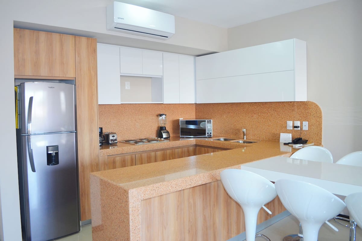 Una cocina moderna con un refrigerador de acero inoxidable, un microondas, un tostador y una encimera de granito.