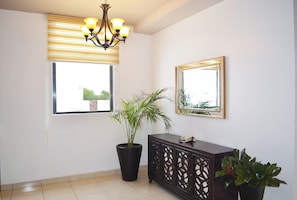 Quarto com planta em vaso, armário, lustre e janela com persianas.