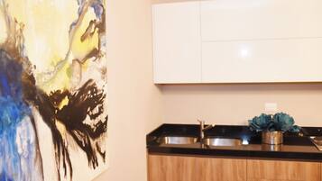 A kitchen with a modern design, featuring a wooden cabinet and a stainless steel sink.