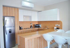 A modern kitchen with a stainless steel refrigerator, a microwave, a coffee maker, and a granite countertop.