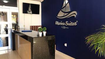 Ein Empfangsschalter mit einer dunkelblauen Wand, die das Logo der Marina Suites und eine Grafik eines Segelboots zeigt.