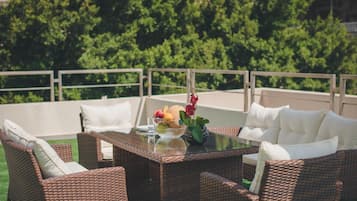 A wicker outdoor seating area with a glass table, white cushions, and a fruit bowl.