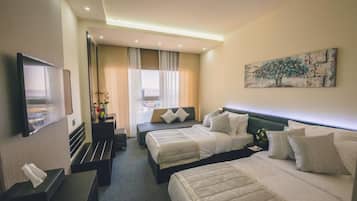 A hotel room with two beds, a flat-screen TV, a desk with a lamp, and a painting on the wall.