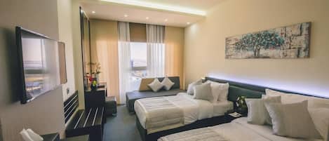 Habitación de hotel con dos camas, un televisor de pantalla plana, un escritorio con lámpara y un cuadro en la pared.