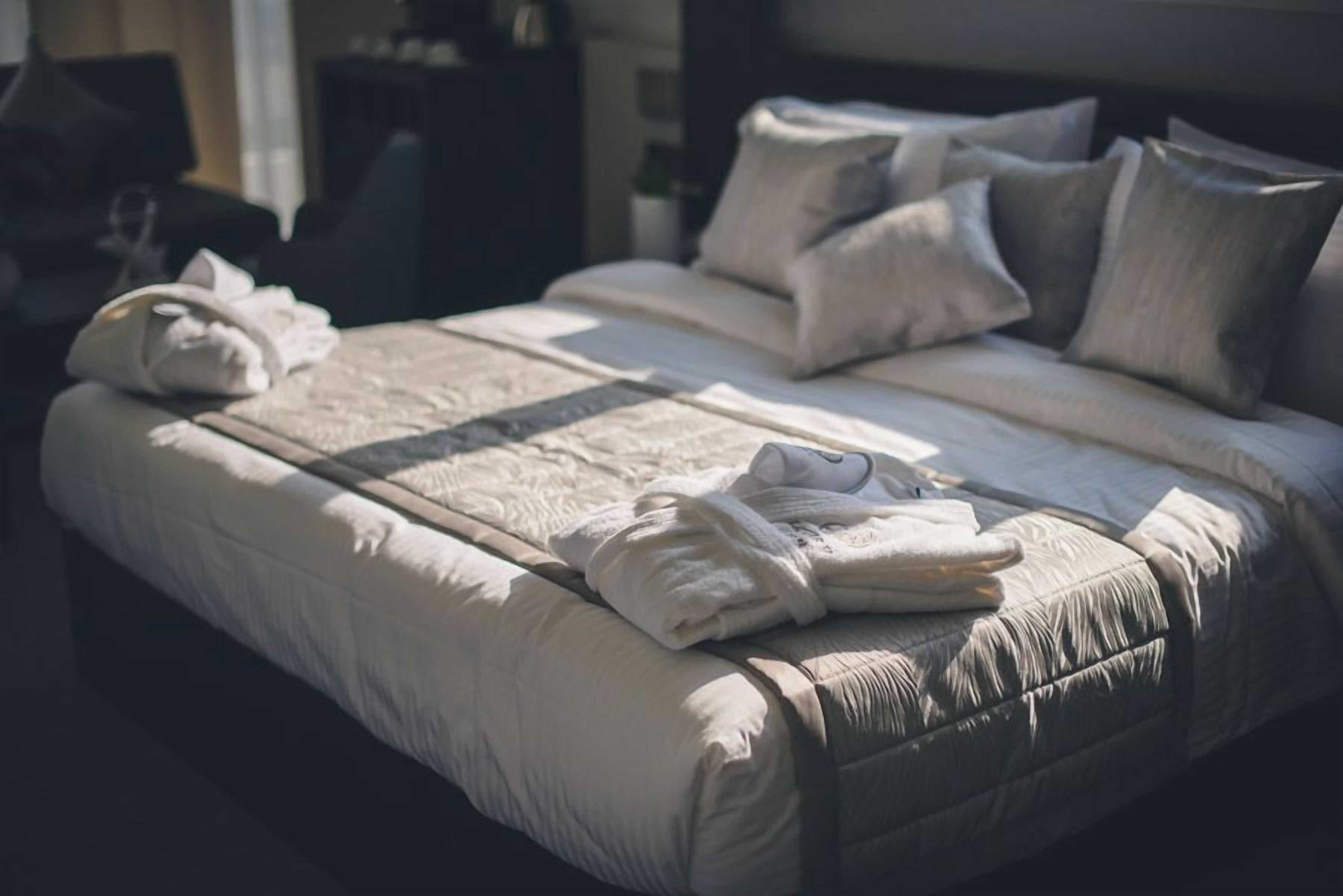 Een net opgemaakt bed met kussens en opgevouwen handdoeken.