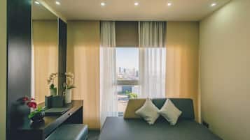 Une chambre d’hôtel moderne, équipée d’un lit, d’une table de chevet, d’un miroir et d’une fenêtre donnant sur la ville.