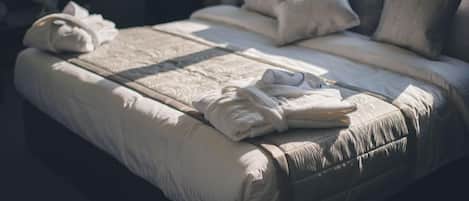 Una cama bien hecha con almohadas y toallas dobladas.
