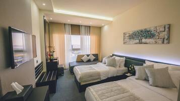 A hotel room with two beds, a flat-screen TV, a desk with a lamp, and a painting on the wall.