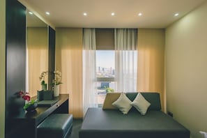 Una habitación de hotel moderna con cama, mesita de noche, espejo y ventana con vista a la ciudad.