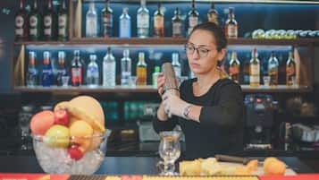 Un barman prépare un cocktail dans un bar, avec une variété de bouteilles en arrière-plan.