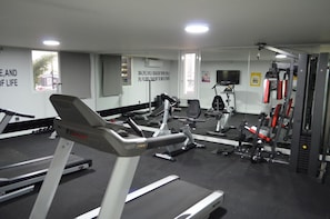 Un gimnasio con cintas de correr, bicicletas estáticas y máquinas de pesas.