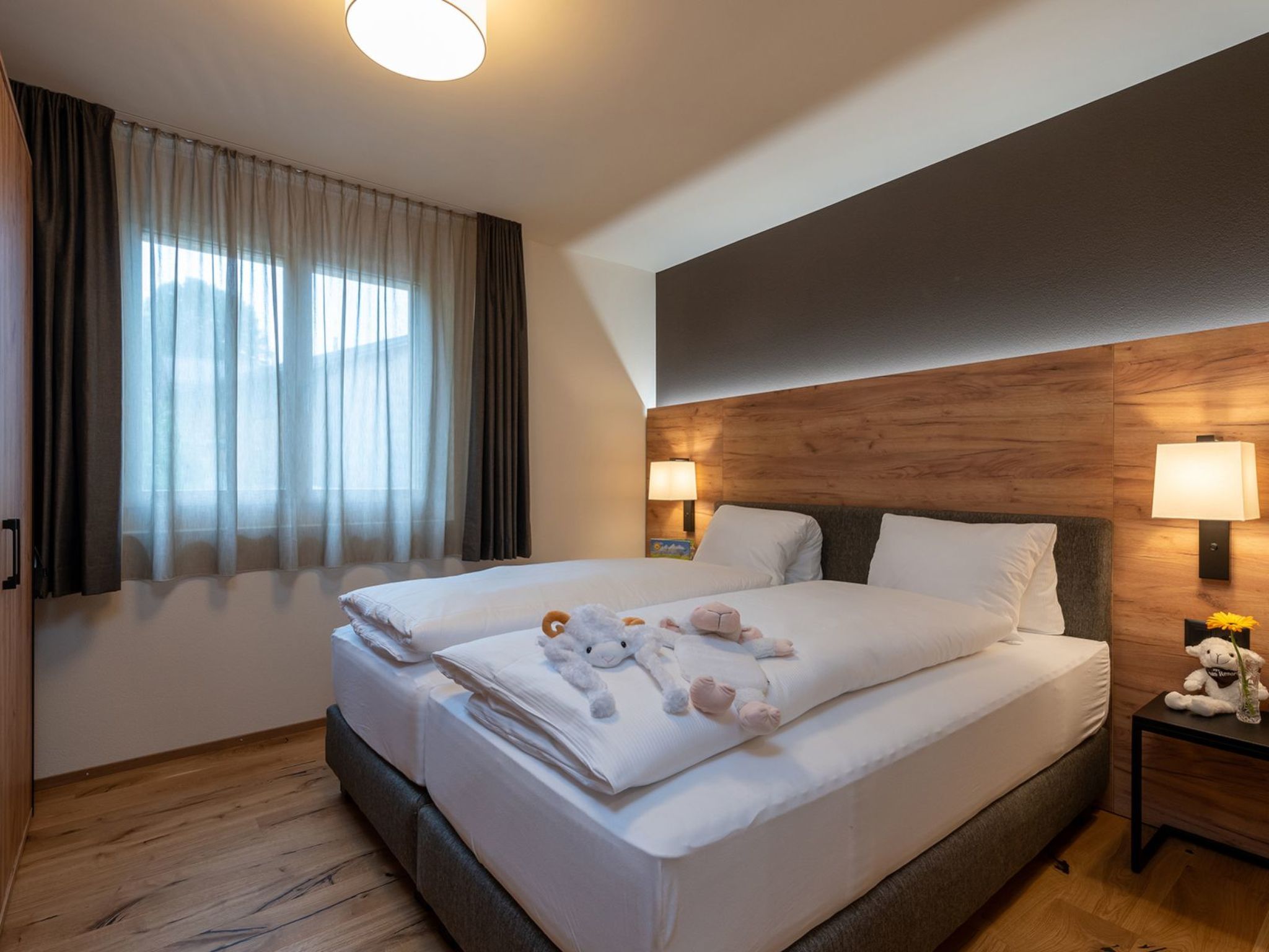 Ein Hotelzimmer mit einem großen Bett, zwei Nachttischlampen, einem hölzernen Kopfteil und einem Fenster mit Vorhängen.