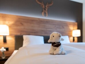 A plush toy on a bed with a wooden headboard, two lamps, and a wall-mounted deer head. - Pradas Resort Brigels, (Breil/Brigels), 65055B by Interhome (Breil/Brigels)