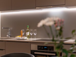 A modern kitchen with a built-in oven, a digital clock, and a wine bottle. - Pradas Resort Brigels, (Breil/Brigels), 65055B by Interhome (Breil/Brigels)