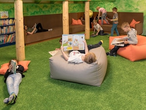 A children's play area with bean bags, books, and a bookshelf. - Pradas Resort Brigels, (Breil/Brigels), 65055B by Interhome (Breil/Brigels)