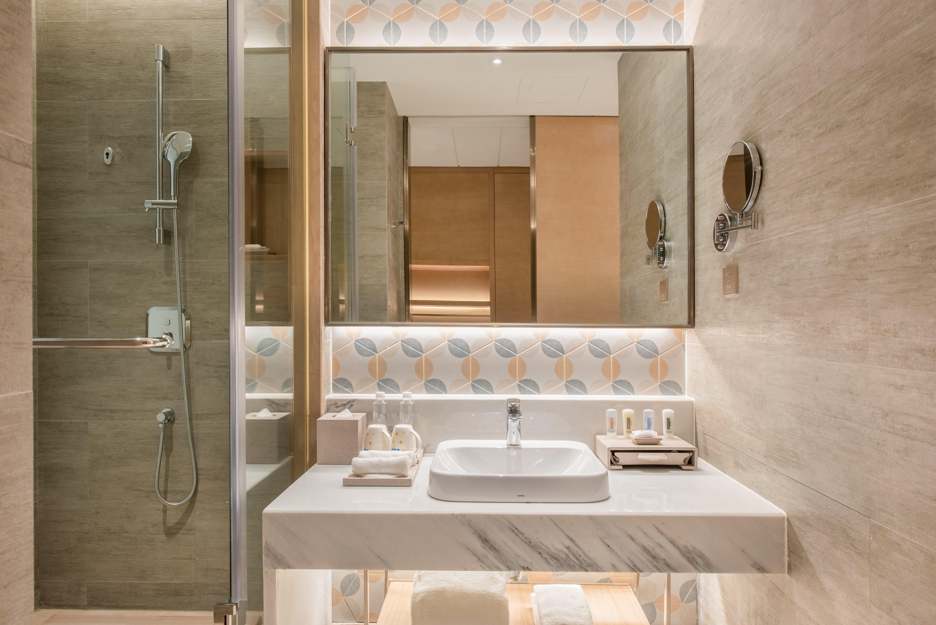 A modern bathroom with a glass-enclosed shower, a marble sink, and a large mirror.