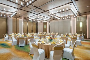 A banquet hall with round tables, white chairs, and gold sashes.