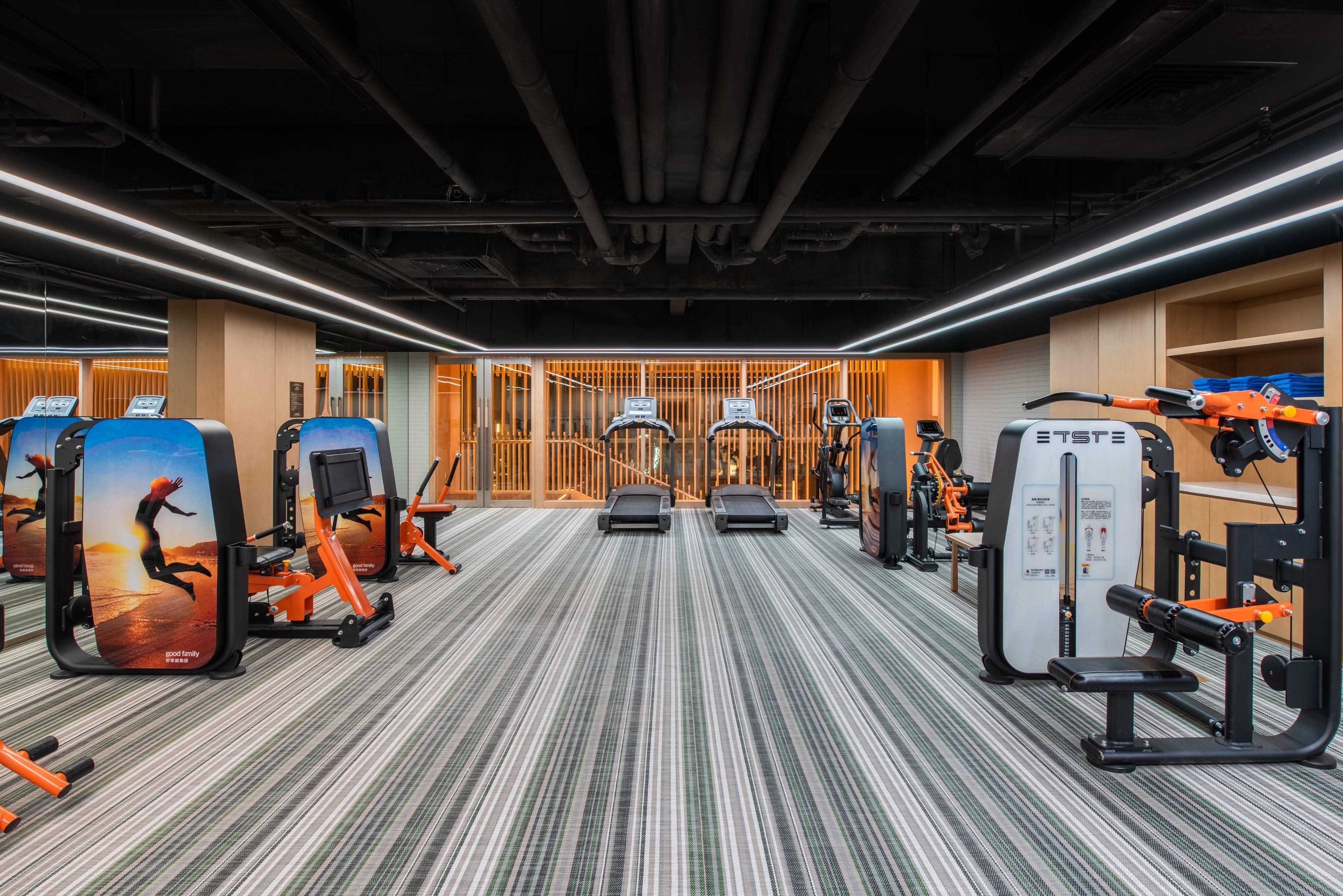 Un gimnasio con equipo de ejercicio, alfombra estampada y diseño de interiores moderno.