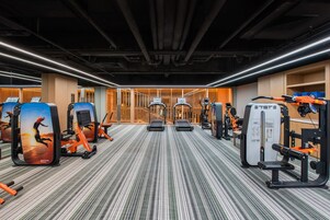 Un gimnasio con equipo de ejercicio, alfombra estampada y diseño de interiores moderno.