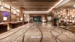 A hotel lobby with a reception desk, seating area, and a decorative wall. - Holiday Inn Resort Yichun Mingyue Mountain (Yichun)