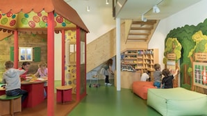 Un área de juegos infantiles con un tobogán, estanterías y una zona de descanso.