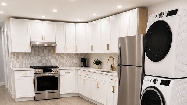 Una cocina moderna con armarios blancos, electrodomésticos de acero inoxidable y suelo de madera.