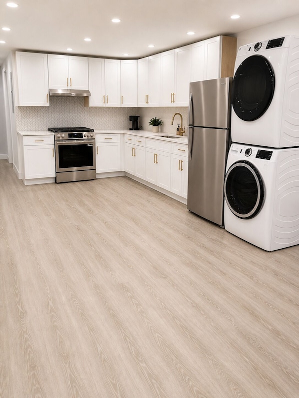 Een moderne keuken met witte kasten, roestvrijstalen apparatuur en een houten vloer.