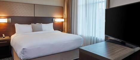 A hotel room with a large bed, a flat-screen TV, and a desk.