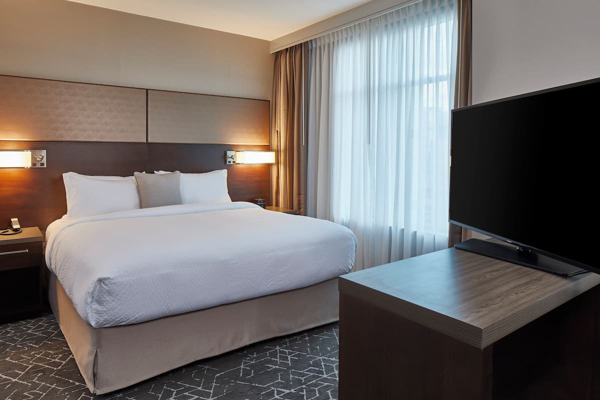 A hotel room with a large bed, a flat-screen TV, and a desk.