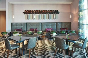 A hotel dining area with a long table, multiple chairs, and a decorative wall piece above the seating. - Residence Inn Nashville Downtown (Nashville)