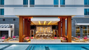 Un moderno vestíbulo de hotel con piscina, bar y zona de estar.