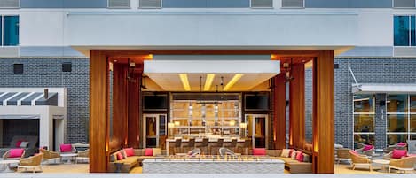 Un hall d’hôtel moderne doté d’une piscine, d’un bar et d’un espace salon.