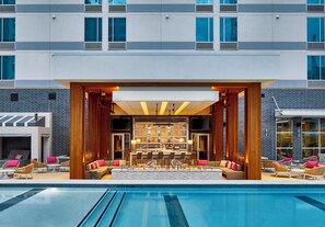 Una hall d'hotel moderna con piscina, bar e area salotto.