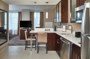 A modern hotel room with a kitchen area, a dining table, chairs, a flat-screen TV, and a large mirror. - Residence Inn Nashville Downtown (Nashville)