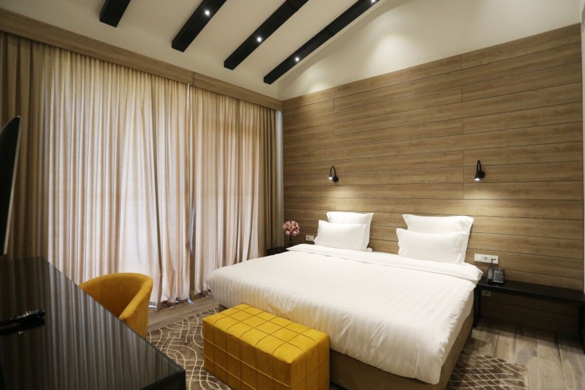 Une chambre d’hôtel moderne avec un grand lit, un bureau et une chaise.