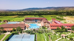 Un hotel con varias piscinas, canchas de tenis y jardines ajardinados.
