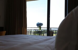 Une chambre d’hôtel avec un grand lit, une fenêtre avec des rideaux et une vue sur la verdure.