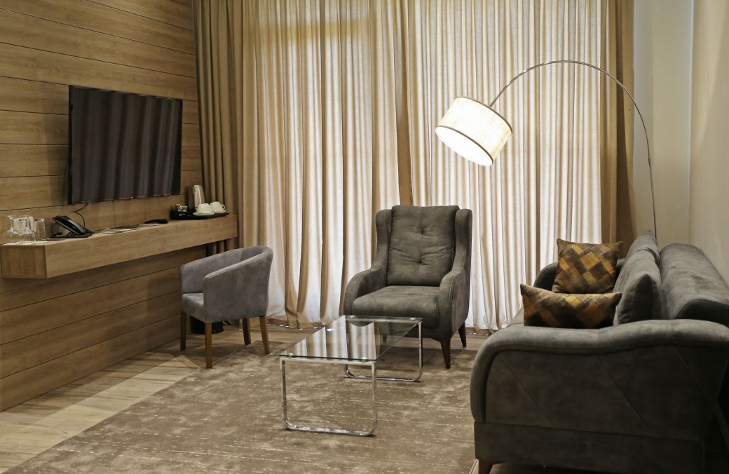 Een moderne woonkamer met een houten accentmuur, een televisie, een bank, een fauteuil en een vloerlamp.