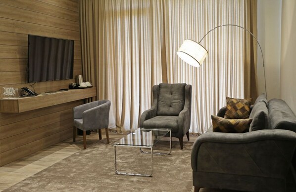 Una sala de estar moderna con una pared de acento de madera, un televisor, un sofá, una silla y una lámpara de pie.