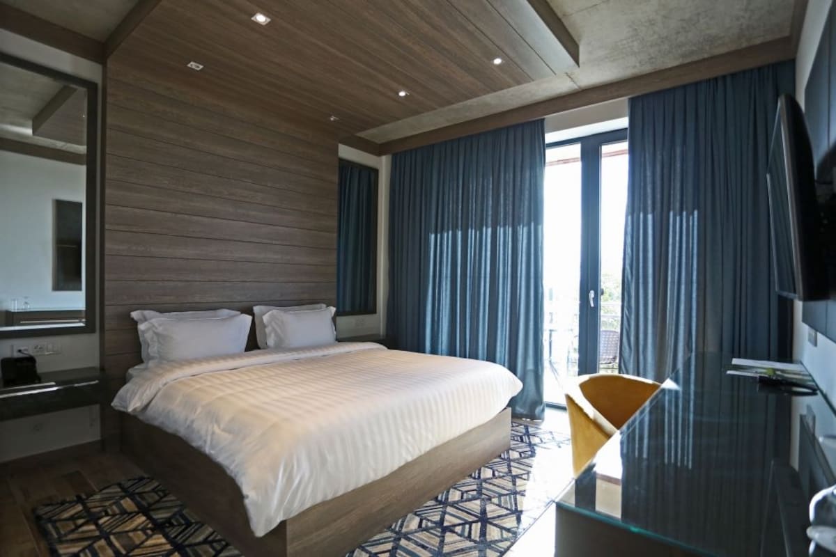 Habitación de hotel moderna con una cama grande, una mesa de vidrio y vistas al exterior.