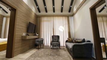 A modern living room with a sofa, armchair, and a desk with a flat-screen TV.