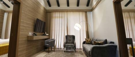 Una sala de estar moderna con sofá, sillón y escritorio con televisor de pantalla plana.