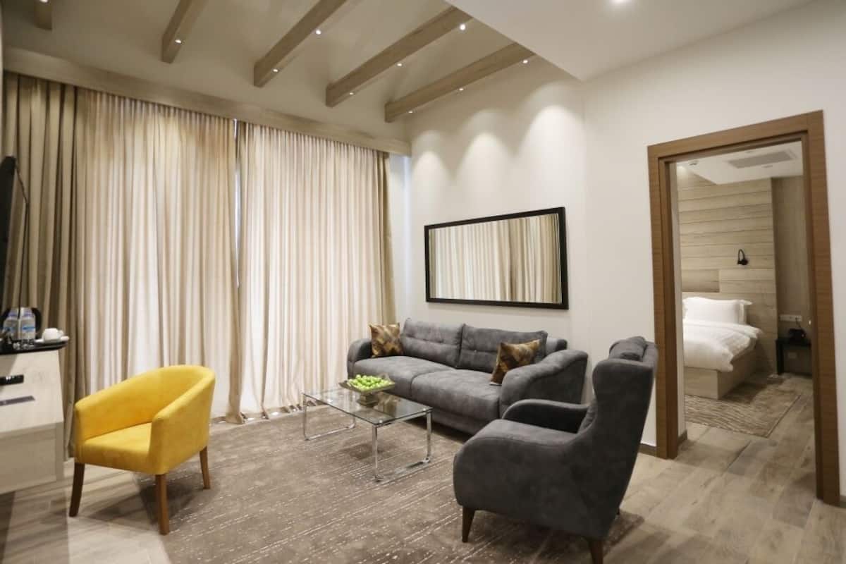A modern living room with a sofa, armchairs, a coffee table, and a TV.