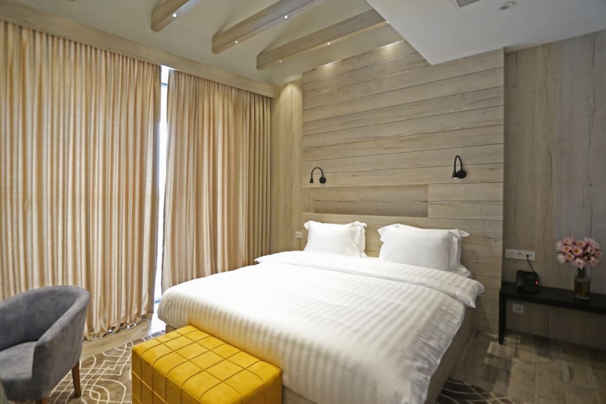 Una habitación de hotel moderna con una cama grande, una silla y una mesita con un florero.