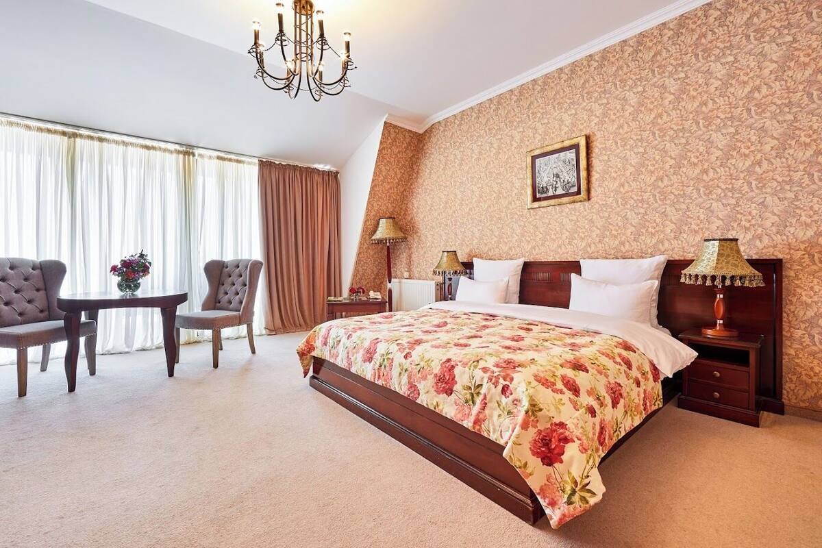 Habitación de hotel con una cama grande, dos sillones, una mesita y un candelabro.