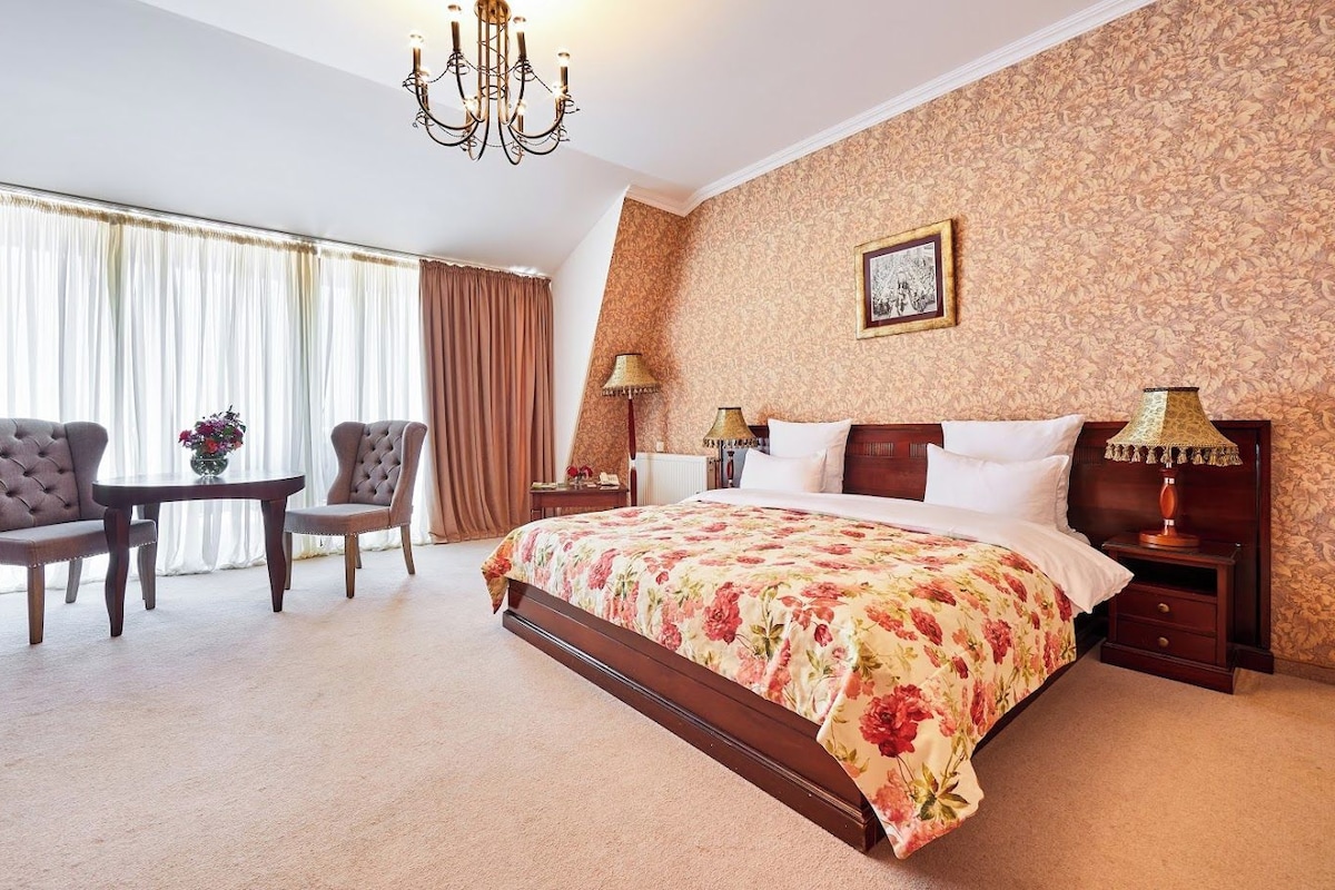 Habitación de hotel con una cama grande, dos sillones, una mesita y un candelabro.